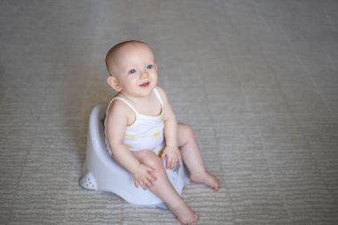 Lazımlıkta oturan bezli şirin bir bebek. Tuvalet ve tuvalet eğitimi. Küçük bir çocuk yararlı bir beceriye alışır. Hijyen. Bebek lazımlık lazımlığında oturuyor..