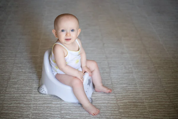 Cute baby in a diaper sitting on a potty. Toilet and potty training. A small child gets used to a useful skill. Hygiene.Baby sitting on a potty toilet stool potty.