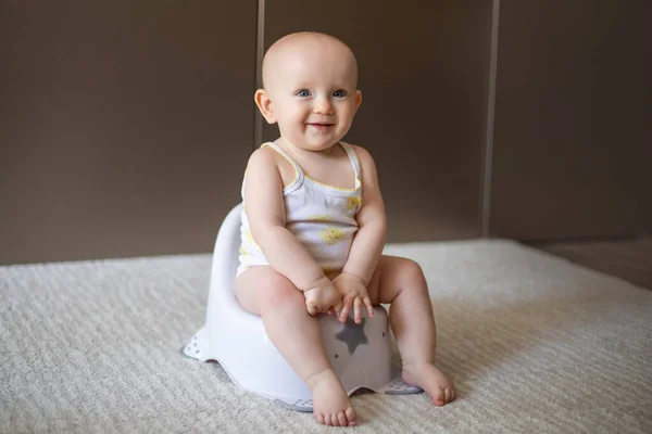 Cute baby in a diaper sitting on a potty. Toilet and potty training. A small child gets used to a useful skill. Hygiene.Baby sitting on a potty toilet stool potty.