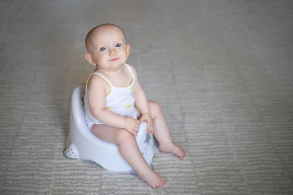 Cute baby in a diaper sitting on a potty. Toilet and potty training. A small child gets used to a useful skill. Hygiene.Baby sitting on a potty toilet stool potty.