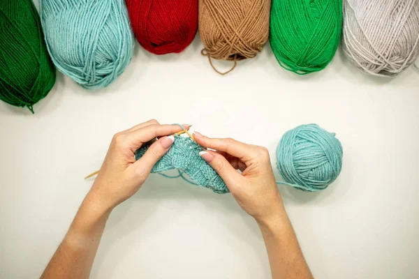 Woman hands knitting hat with needles and yarn.