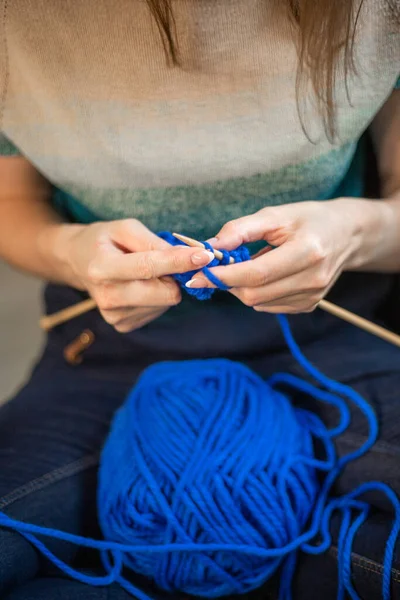 woman knitting a sweater from blue yarn.