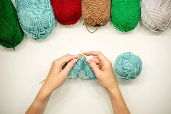 Woman hands knitting hat with needles and yarn.