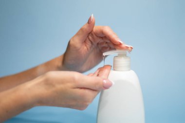 Ellerini yıkama. Jung 'un elleri, ellerini yıkamak için sıvı sabun, koronavirüs salgınından korunmak için hijyen konsepti, mavi beyaz arka planda izole edilmiş, yakın plan..