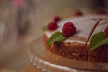 Kafedeki ahududu ve nane yapraklarıyla süslenmiş beyaz kremalı pasta..