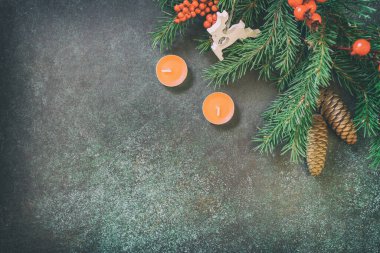 Noel 'de köknar ağacı dalları, mumlar ve koyu yeşil taş arka planda Noel süslemeleri vardı. Boşluğu kopyala. 