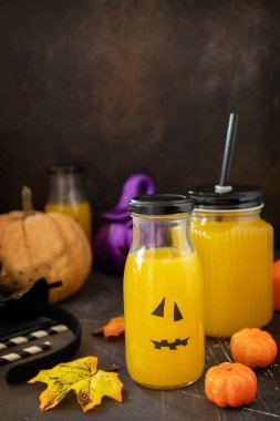 Cadılar bayramı masasında balkabağı içeceği ve Cadılar Bayramı balkabakları, fener ve karanlık taş arka planda süsleme. Boşluğu kopyala.