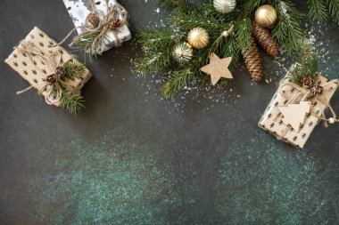 Tatil konsepti. Yılbaşı ya da yeni yıl planı köknar ağacı dalı ve koyu yeşil taş arka planda Noel hediyesi. Düz yat, boşluğu kopyala.