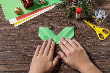 Talimat 5: Noel tebrik kartı hediye origami mumu ahşap masada. Çocuk sanat projesi, el yapımı, çocuklar için el işi..