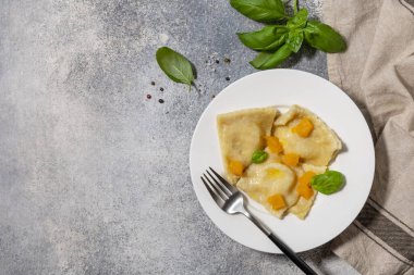 Gri bir masa üstünde ev yapımı İtalyan balkabağı ricotta ravioli. Üst görünüm düz arkaplan. Boşluğu kopyala.