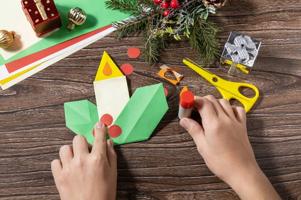 Talimat 12. adım. Noel tebrik kartı hediye origami mumu ahşap masada. Çocuk sanat projesi, el yapımı, çocuklar için el işi..