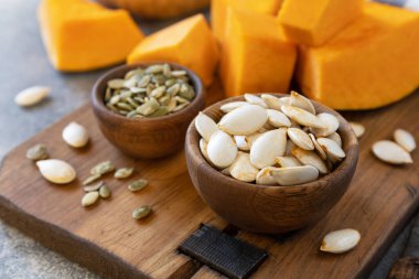 Çiğ süper yiyecekler hasattan sonra kabak tohumları. Gri taş arka planda tahta kasede kabak tohumları.