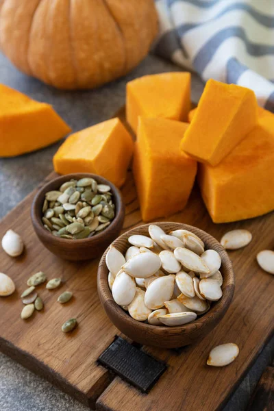 Çiğ süper yiyecekler hasattan sonra kabak tohumları. Gri taş arka planda tahta kasede kabak tohumları. 