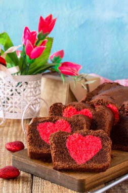 Sevgililer günü, doğum günü ya da Anneler Günü tatlısı, ev yapımı şenlikli yemekler. Ahşap bir masa üstünde kırmızı kalpli ev yapımı çikolatalı kek. Boşluğu kopyala.