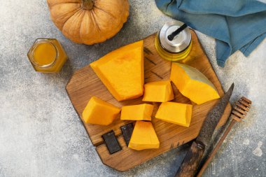 Raw pumpkin and honey for prepare baking over gray stone background. Top view flat lay. 