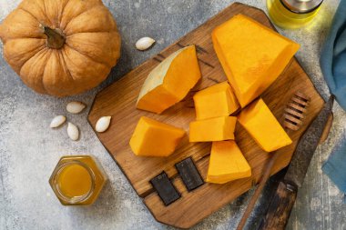Raw pumpkin and honey for prepare baking over gray stone background. Top view flat lay. 