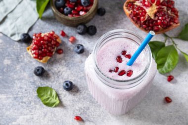 Taş bir masanın üstünde nar ve yaban mersininden yapılmış vejetaryen protein içeceği. Sağlıklı yiyecekler. Yaşam tarzı sağlıklılığı. Foodizm, saflık, çiğ gıda diyeti.