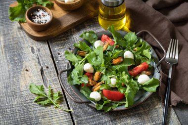 Tahta bir masada roka, mozzarella, midye ve salata soslu sağlıklı diyet salatası. Düşük kalorili diyet yemeği. 