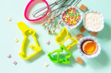 Pişirme ya da pişirme geçmişi. Paskalya festivali için gerekli malzemeler. Mutfak aletleri, un, esmer şeker, açık yeşil arka planda yumurta ve tereyağı. Üst görünüm düzlüğü.