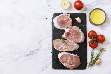 Raw meat steaks for grilling. Steaks raw turkey with vegetables and spices on a marble tabletop. Top view flat lay background. Copy space. 
