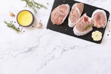 Raw meat steaks for grilling. Steaks raw turkey with rosemary and spices on a marble tabletop. Top view flat lay background. Copy space. 