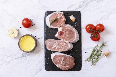 Raw meat steaks for grilling. Steaks raw turkey with vegetables and spices on a marble tabletop. Top view flat lay background. 