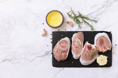 Raw meat steaks for grilling. Steaks raw turkey with rosemary and spices on a marble tabletop. Top view flat lay background. Copy space. 
