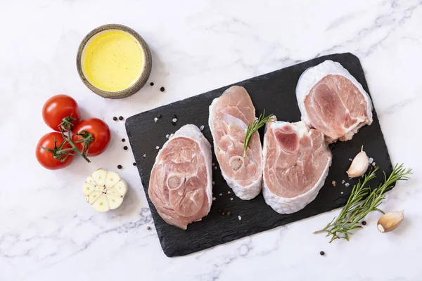 Raw meat steaks for grilling. Steaks raw turkey with vegetables and spices on a marble tabletop. Top view flat lay background. 