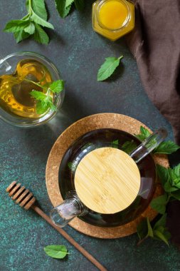 Therapeutic herbal green tea. Hot tea with honey mints in a glass teapot on a stone table. Top view flat lay.