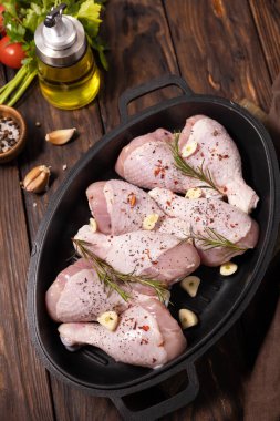 Raw chicken meat. Uncooked chicken legs on wooden cooking table background with spices. 