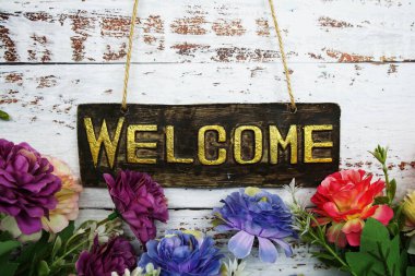 Hoş geldiniz. Ahşap arka planda çiçek çerçeveli işaret.