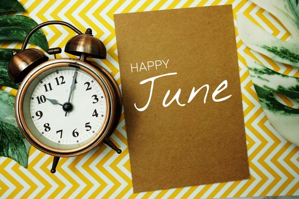 目覚まし時計とモンステラの休暇を持つ紙カード上のハッピー6月タイポグラフィのテキスト — ストック写真