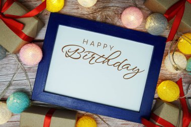 Tahta zemin üzerinde LED pamuk topu olan doğum günü kartı tipografisi metnin kutlu olsun.