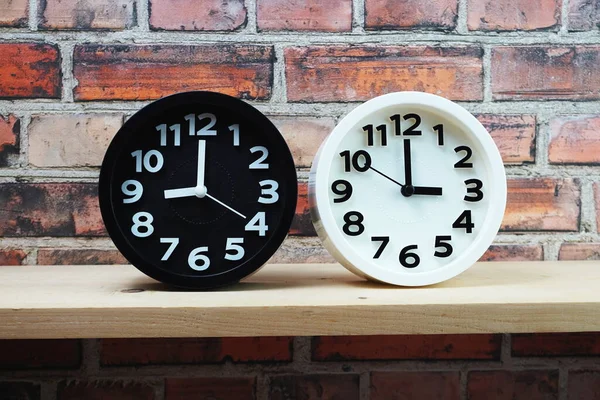 Ahşap raflarda ve tuğla duvar arka planında farklı ülkelerin zaman dilimine sahip saatler