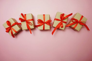 Pembe arka planda kırmızı kurdeleli hediye kutuları