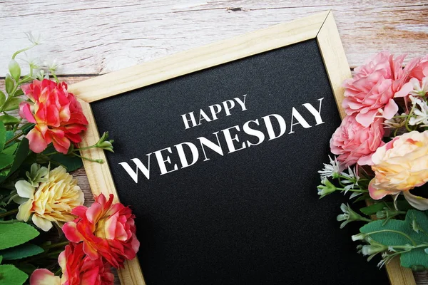 Ahşap arka planda çiçek buketiyle süslenmiş kara zemin üzerine Mutlu Çarşamba metinleri