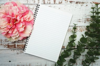 Alarmlı saati ve tahta arka planı olan boş sayfaları olan bir defter.