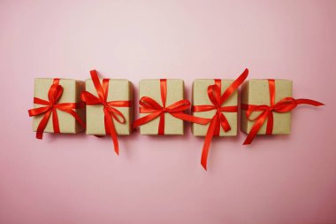 Pembe arka planda kırmızı kurdeleli hediye kutuları