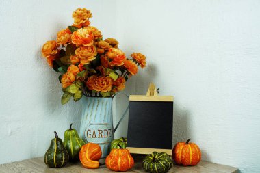 Tahta sehpa yapay çiçekler ve ahşap masa dekorasyonunda balkabağı ile süslenir.