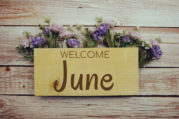 木製の背景に花のフレームと木製ボード上の歓迎6月のテキスト — ストック写真