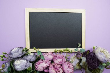 Mor arkaplanda çiçek buketi olan boş karatahta