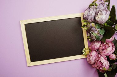 Mor arkaplanda çiçek buketi olan boş karatahta