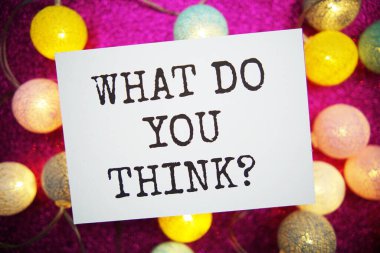 Sen ne düşünüyorsun? Pembe arkaplanda LED pamuk topları olan kağıt kart üzerine metin