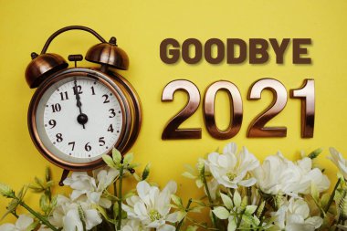 Güle güle 2021 yazıları çalar saat ve sarı arkaplanda çiçek süslemesi