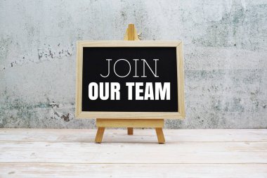 Join Our Team typography text on the blackboard set on wooden floor and brick background