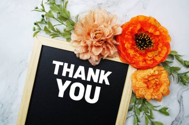 Thank You text on blackboard with flower decoration flat lay on marble background