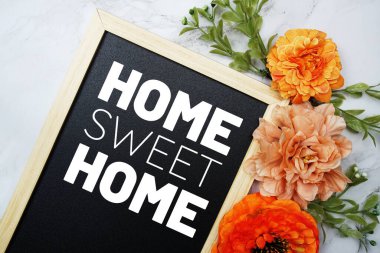 Home Sweet Home text on blackboard with flower decoration flat lay on marble background