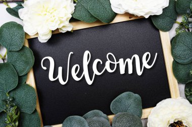 Welcome text on blackboard and eucalyptus leaves decoration on marble background