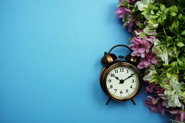 青い背景に花のフレームの装飾と目覚まし時計 — ストック写真