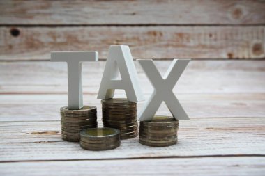 Tahta zemin üzerinde bozuk para yığını olan vergi alfabesi harfleri